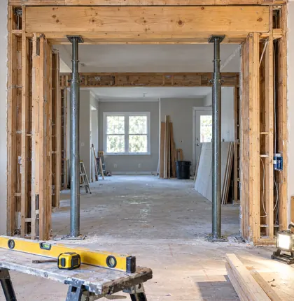 Opened interior wall with a new wooden header beam and temporary steel shoring posts