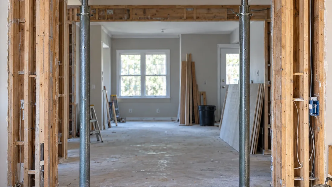 Opened interior wall with a new wooden header beam and temporary steel shoring posts