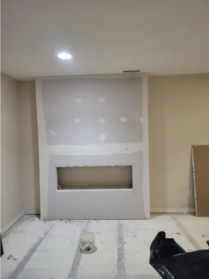The same wall after drywall, with the fireplace opening cut out and the seams taped and floated