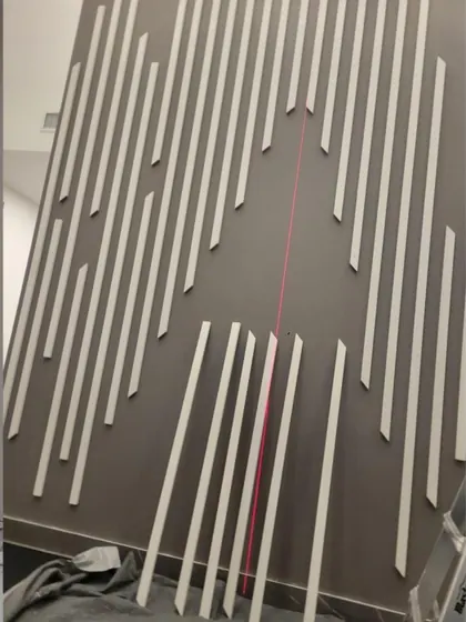 White wood slats laid out on a painted feature wall against a laser line to keep the spacing even