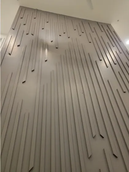 The completed slat wall seen from the side, lit by ceiling spotlights