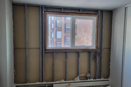 An exterior wall opened down to the steel studs around a window, with the old insulation removed