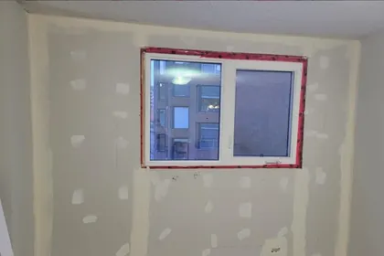 The same wall drywalled, taped and ready for paint around the window